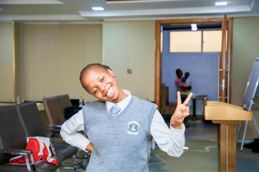 A smiling schoolboy giving a peace sign