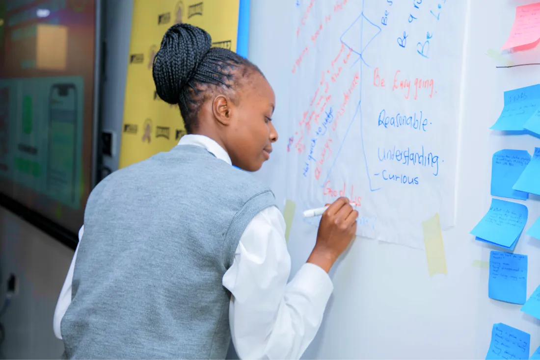 A student writing reflections on a whiteboard